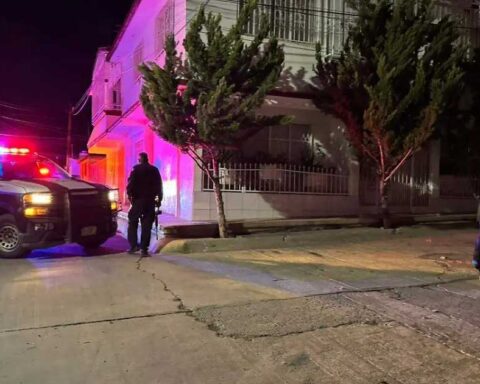 Una patrulla y dos policías afuera del casa de la que sacaron a dos adolescentes en Chihuahua.