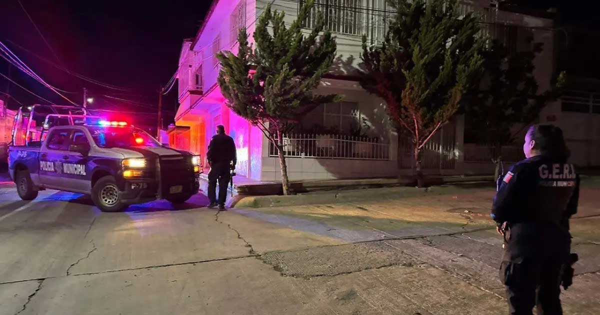 Una patrulla y dos policías afuera del casa de la que sacaron a dos adolescentes en Chihuahua.