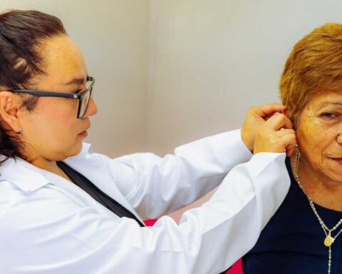Doctora colocando un aparato auditivo a una mujer mayor.