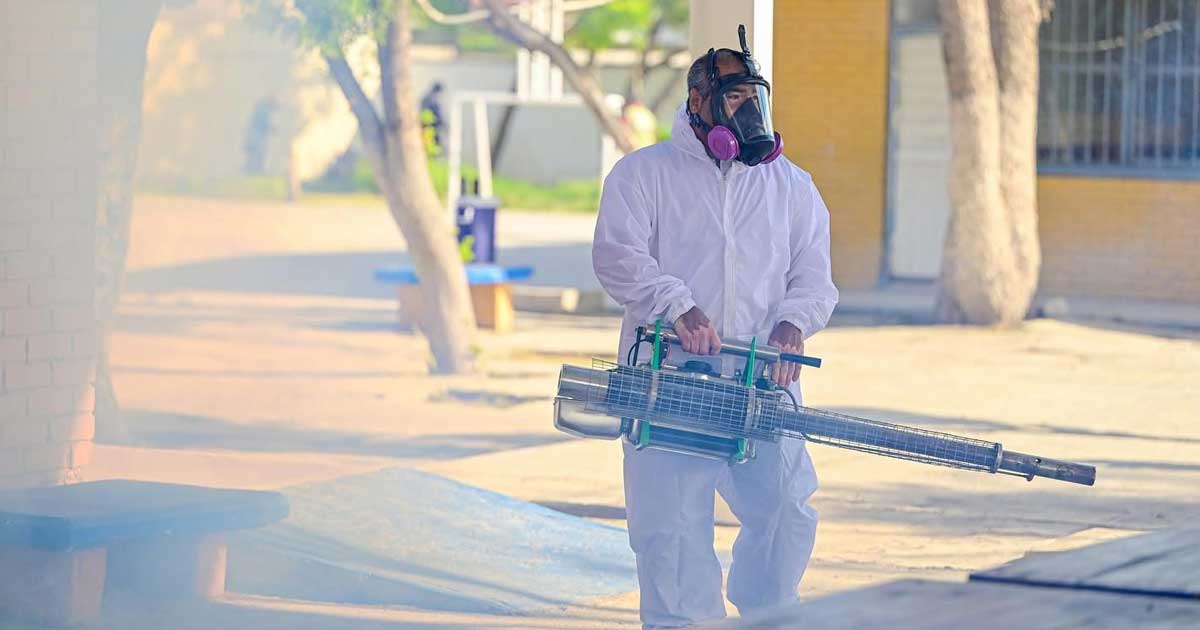 Trabajador fumigando dentro de una escuela.