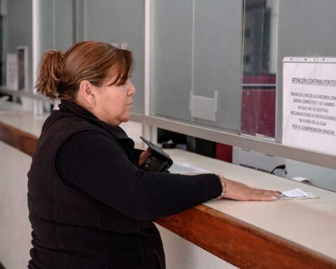 Mujer pagando impuestos en ventanilla.