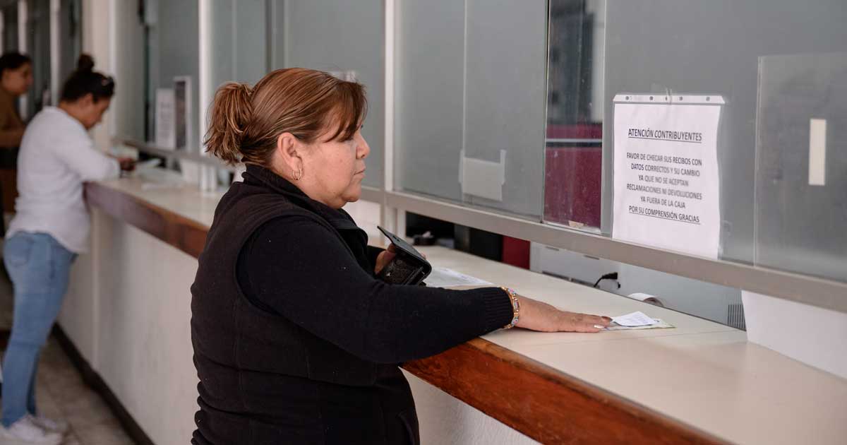 Mujer pagando impuestos en ventanilla.