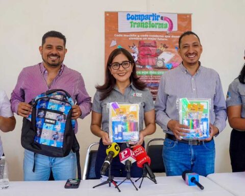 Funcionarios sosteniendo mochilas y útiles escolares.