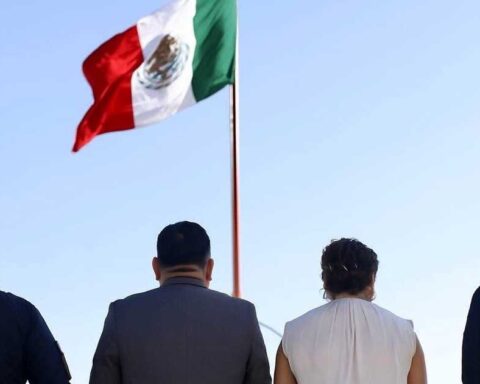 Funcionarios frente a la bandera izada.