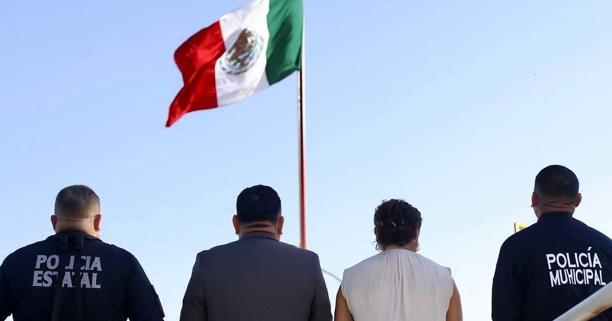 Funcionarios frente a la bandera izada.