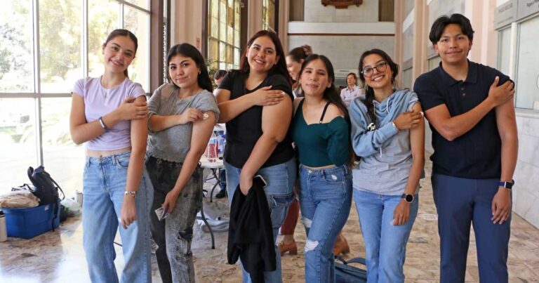 Jóvenes mostrando su brazo vacunado en la UAdeC.