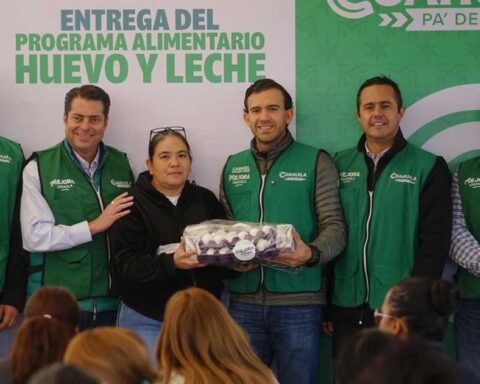Gabriel Elizondo, de Mejora Coahuila, y otros funcionarios entregando un cono de huevo a una beneficiaria.
