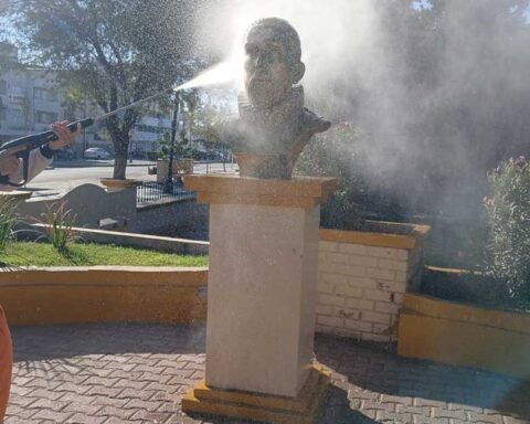 Trabajador de La Ola lavando con una manguera un monumento en Torreón.