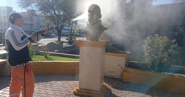Trabajador de La Ola lavando con una manguera un monumento en Torreón.