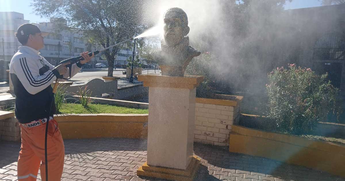 Trabajador de La Ola lavando con una manguera un monumento en Torreón.