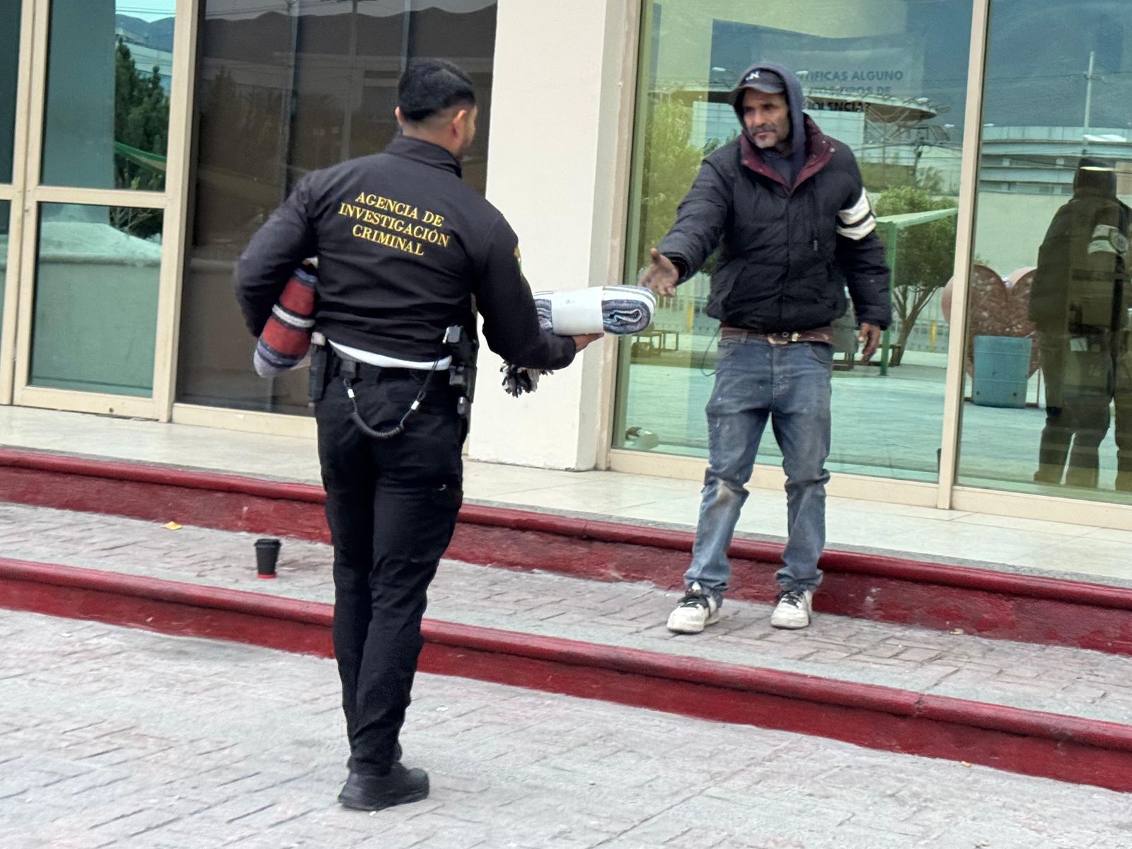 Elemento de la AIC entregando una cobija a un hombre en Saltillo.