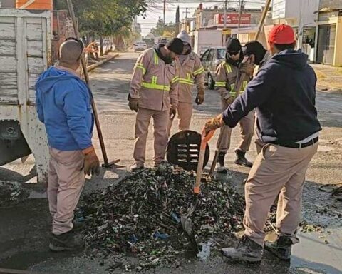 Trabajadores alrededor de las miles de taparroscas sacadas de una alcantarilla en Torreón.