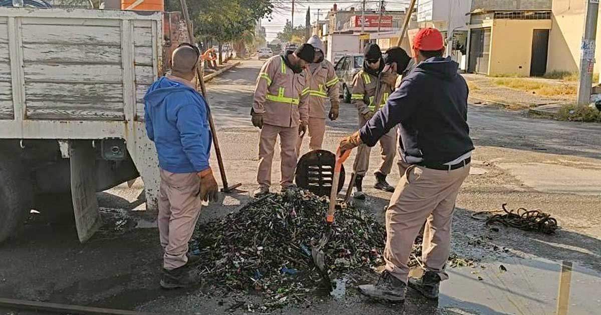 Trabajadores alrededor de las miles de taparroscas sacadas de una alcantarilla en Torreón.