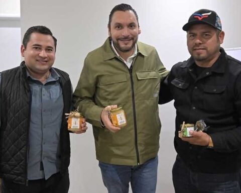 Alcalde Carlos Villarreal y empresarios sosteniendo tarros de miel.