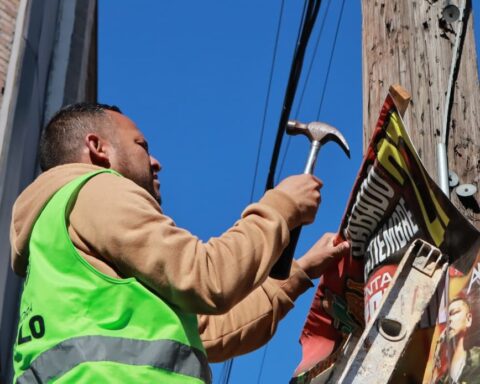 Trabajador de Saltillo retirando publicidad de un poste en el centro histórico.