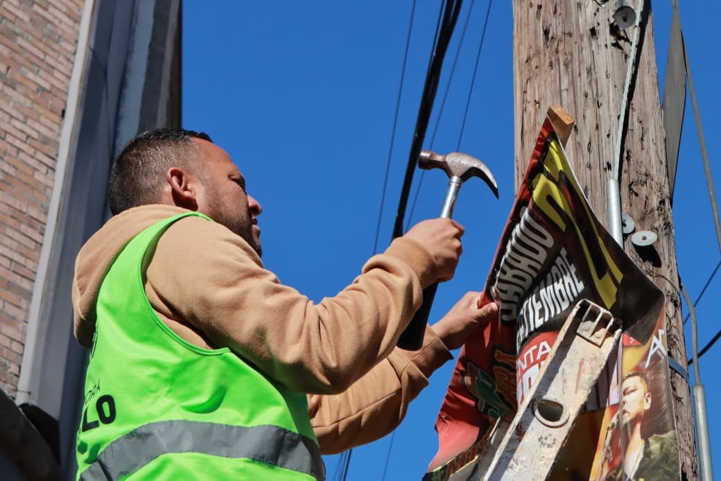 Trabajador de Saltillo retirando publicidad de un poste en el centro histórico.