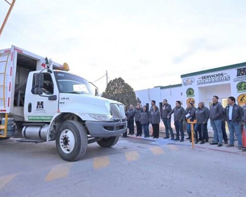 Camión de recolección de basura en primer plano; alcalde y trabajadores municipales, en segundo plano.