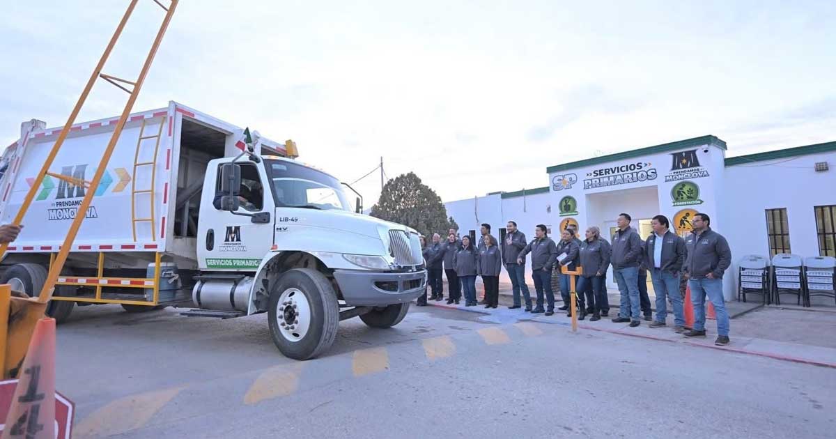 Camión de recolección de basura en primer plano; alcalde y trabajadores municipales, en segundo plano.