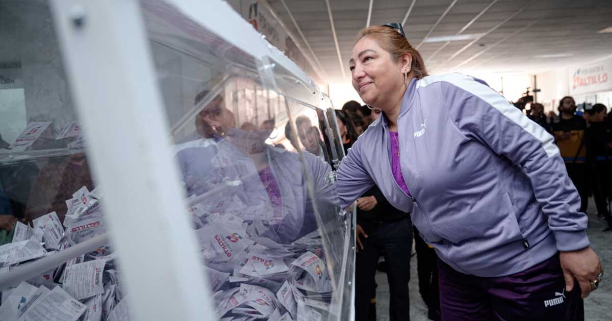 Mujer sacando un boleto de una urna para el sorteo en Saltillo.
