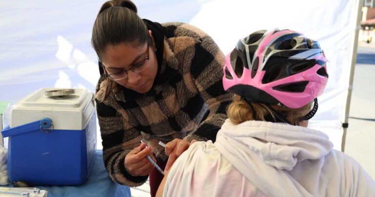 Mujer vacunando a una persona.