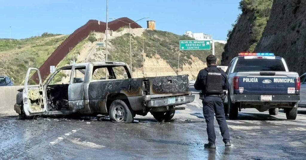Un agente de la Policía en la escena de una camioneta quemada en una carretera.