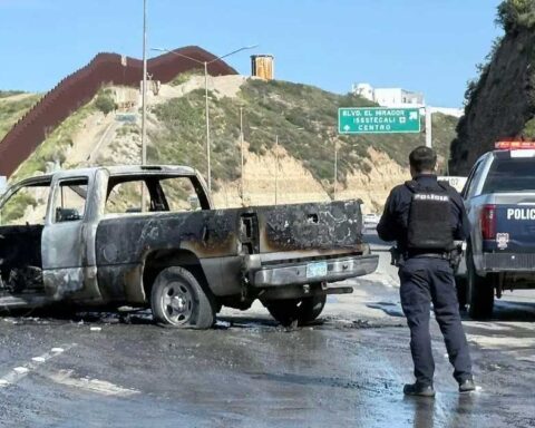 Un agente de la Policía en la escena de una camioneta quemada en una carretera.