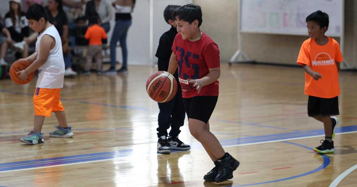 Niños jugando basquetbol en cancha interior de Saltillo.