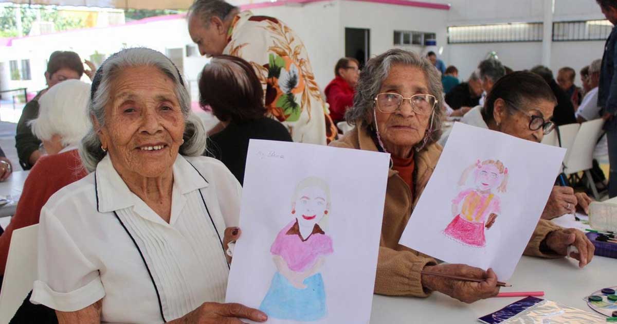 Mujeres del Club de los Abuelos del DIF Torreón mostrando sus dibujos.