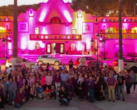 Ayuntamiento de Ramos Arizpe iluminado de rosa y un grupo numeroso de mujeres al frente.