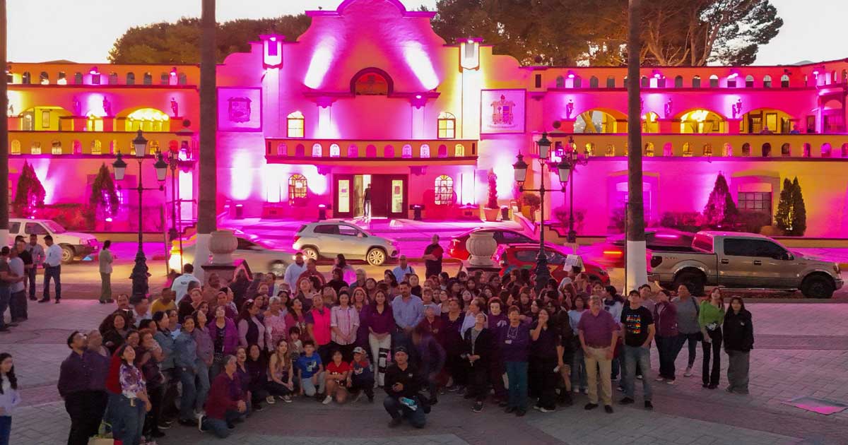 Ayuntamiento de Ramos Arizpe iluminado de rosa y un grupo numeroso de mujeres al frente.
