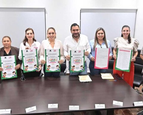 Funcionarios sosteniendo la convocatoria para el Cabildo Infantil.