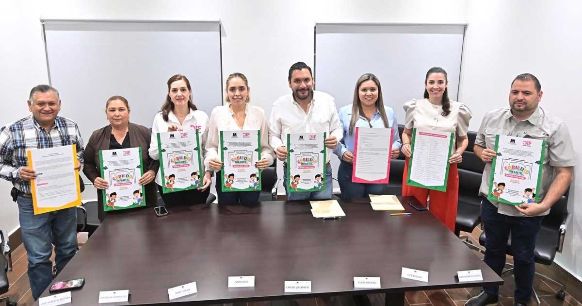Funcionarios sosteniendo la convocatoria para el Cabildo Infantil.