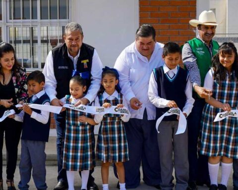 Estudiantes al frente y funcionarios atrás cortando un listón en escuela de Ramos Arizpe.