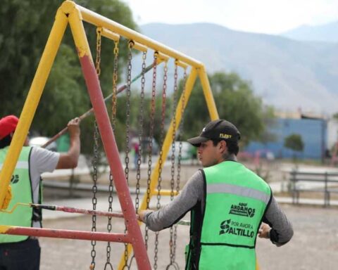 Trabajadores de Saltillo pintando columpios en plaza pública.