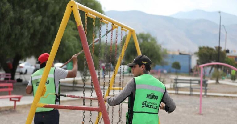 Trabajadores de Saltillo pintando columpios en plaza pública.