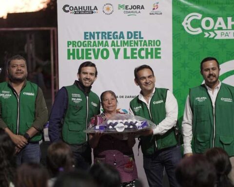 Funcionarios entregando apoyo alimentario a una mujer.