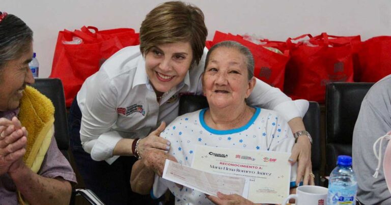 La presidenta del DIF Torreón abrazando y dando un reconocimiento en papel a una adulta mayor.