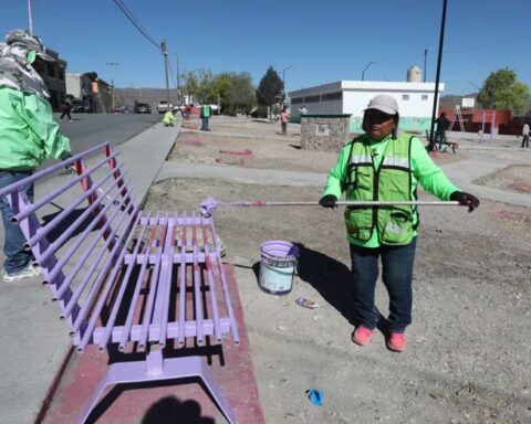 Trabajadoras pintando una banca en plaza pública al sur de Saltillo.