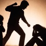 Siluetas de un hombre ejerciendo violencia familiar contra una mujer y un niño observando.