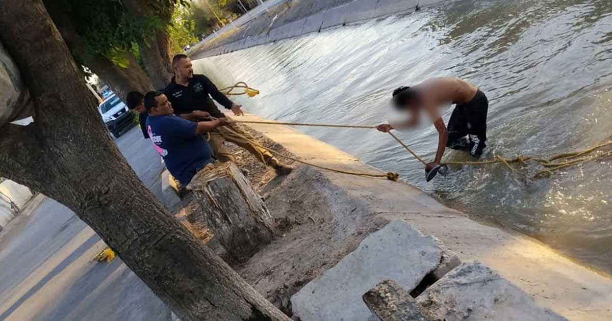 Elementos de PC sacando con una cuerda a un joven en un canal de riego en San Pedro, Coahuila.