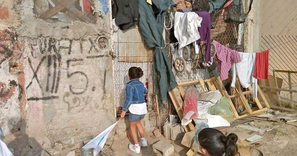 Una niña en el exterior de una casa que muestra pobreza y rezago social.