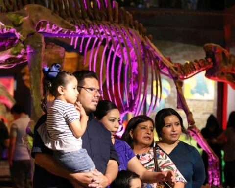 Familia visitando el Museo del Desierto en Saltillo con un esqueleto de dinosaurio en la parte posterior.