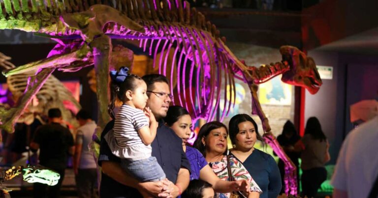 Familia visitando el Museo del Desierto en Saltillo con un esqueleto de dinosaurio en la parte posterior.