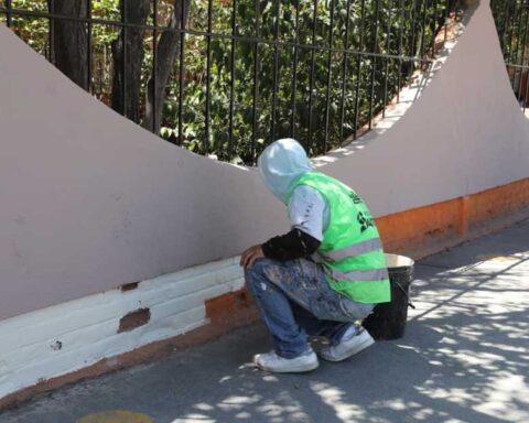 Trabajador aplicando pintura a una barda de la plaza en Saltillo.