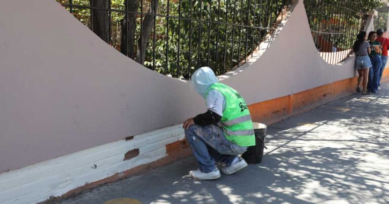 Trabajador aplicando pintura a una barda de la plaza en Saltillo.