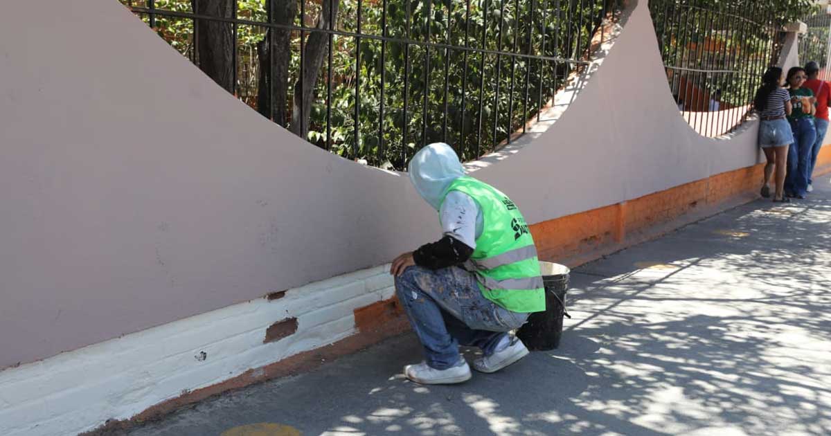 Trabajador aplicando pintura a una barda de la plaza en Saltillo.