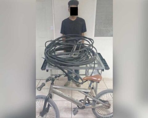 El hombre detenido y delante de él el cableado y la bicicleta presuntamente robados.