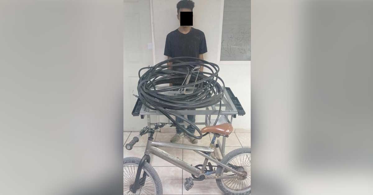 El hombre detenido y delante de él el cableado y la bicicleta presuntamente robados.