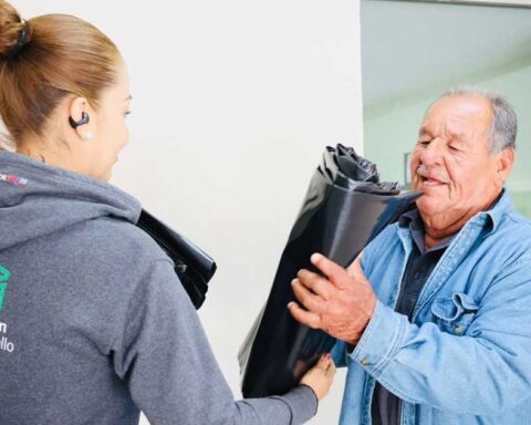 Funcionaria entregando hule a un hombre.