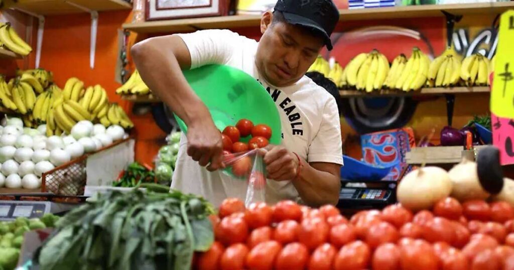 Vendedor despechando jitomate en un mercado.